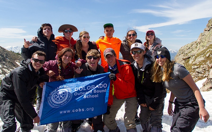 a group of students smile at the camera while standing on a snowy and rocky landscape
